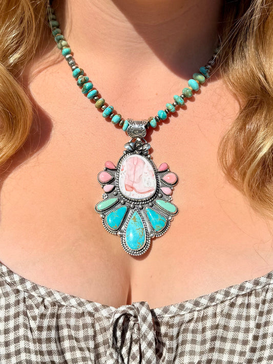 Handmade porcelain cowboy boot pendant with Royston turquoise, pink conch, and sterling silver succulent detail worn outdoors