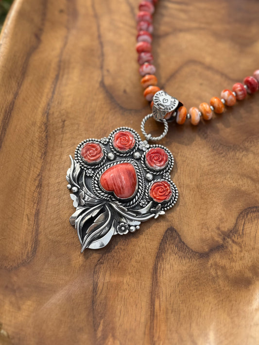Close-up of red spiny oyster stones set in sterling silver paw pendant, detailed handcrafted dog lover jewelry