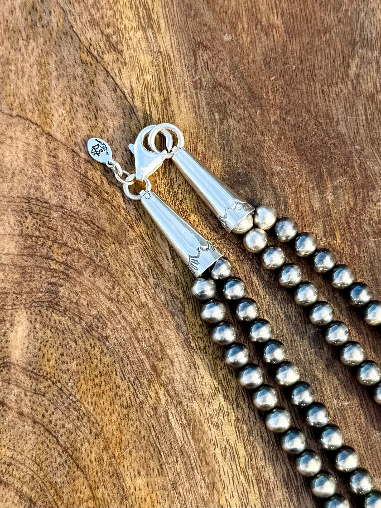 Close up of hand stamped detail on the ends of Squash blossom necklace