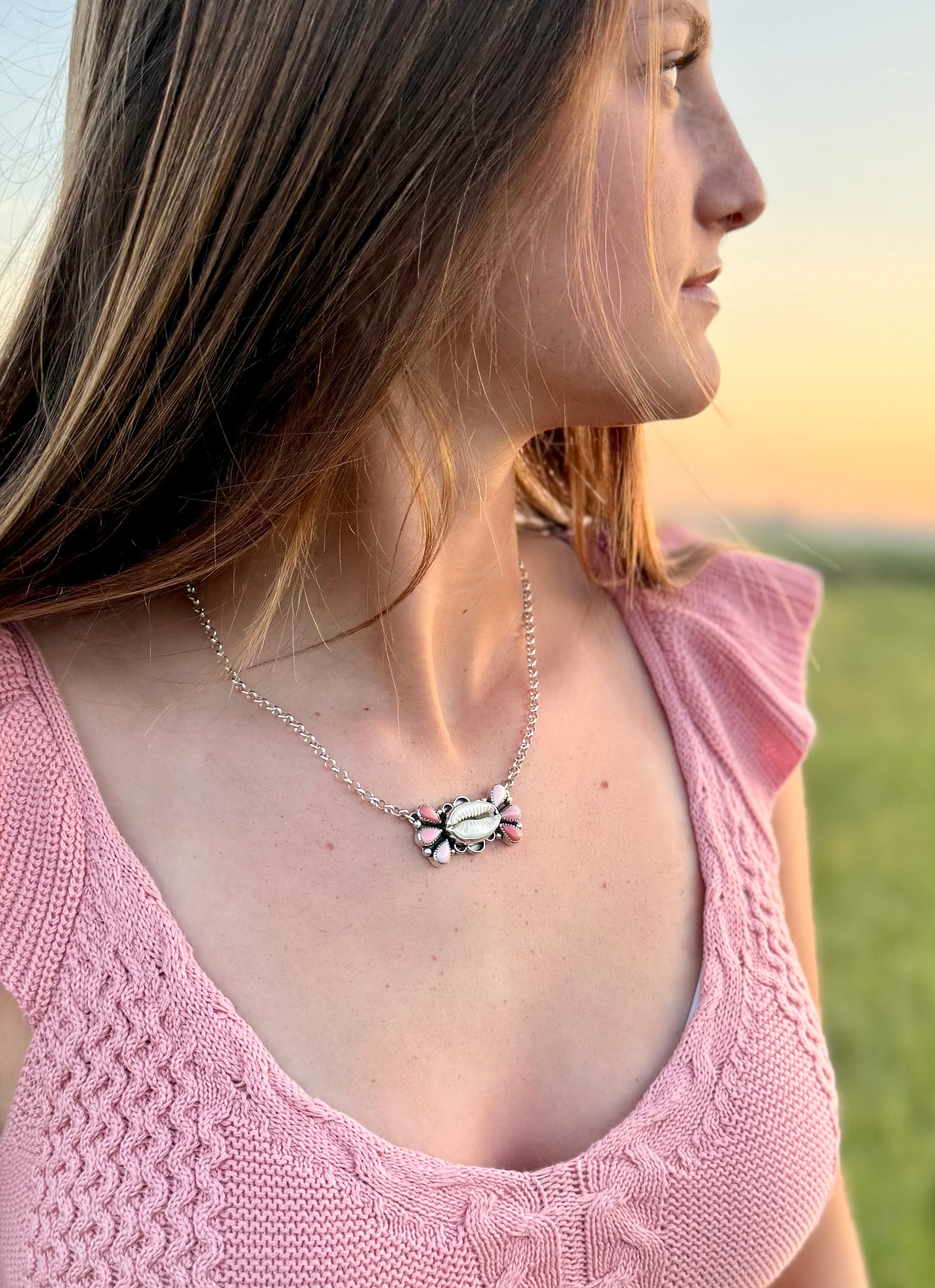 Woman wearing a pink pink conch necklace with a blurred background