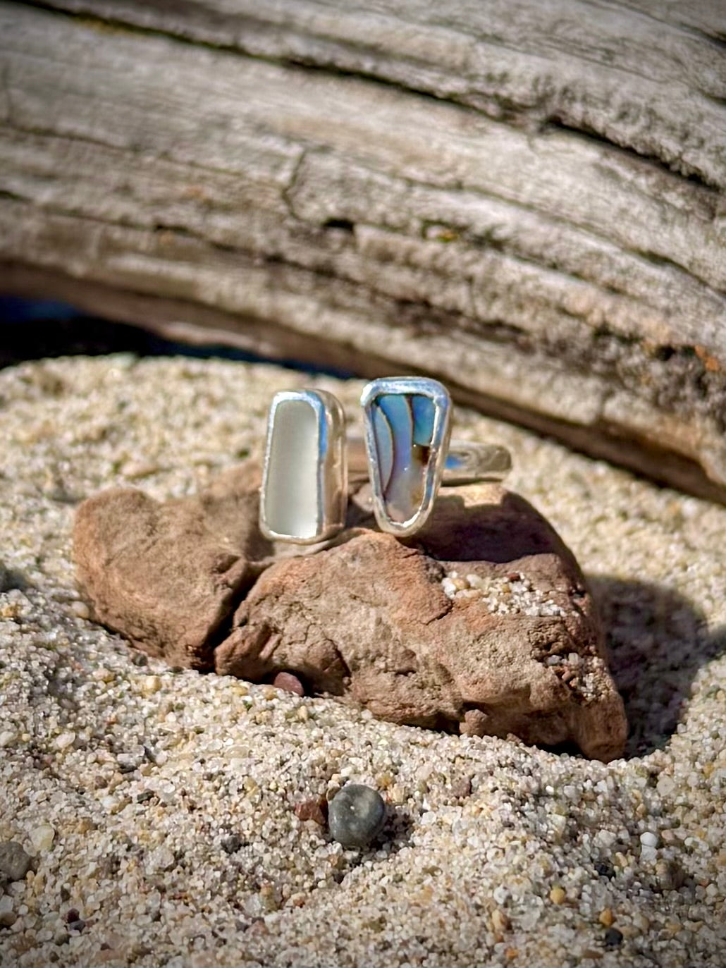Silver ring with beach glass on a rock in the sand
