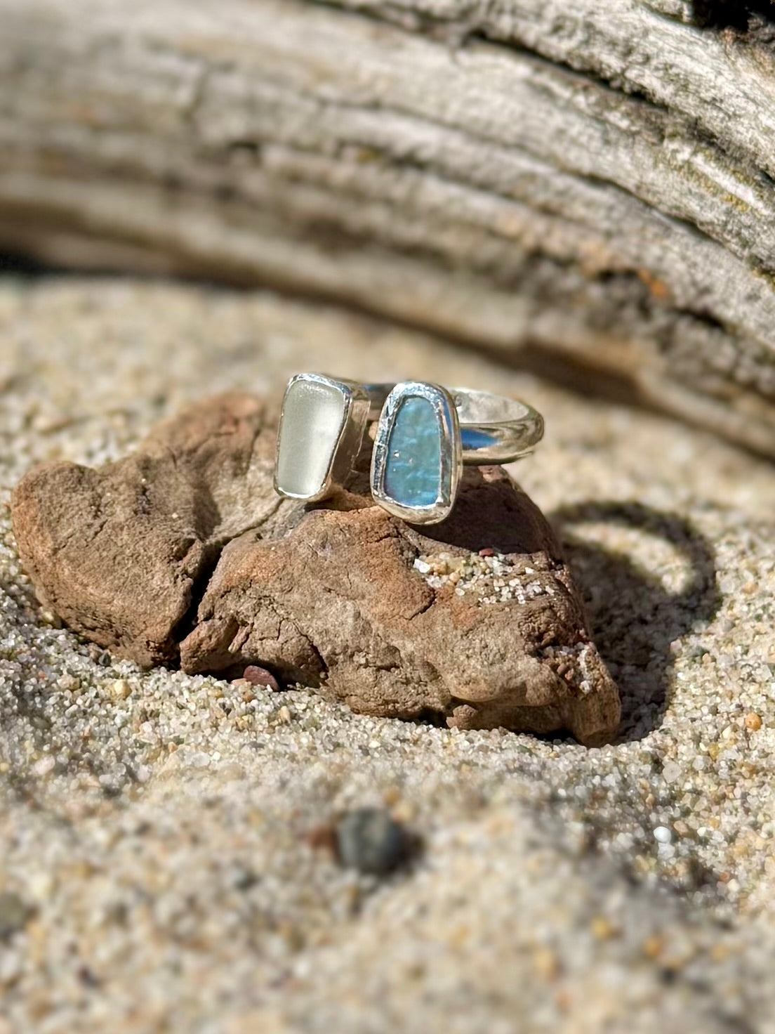 Abalone and beach glass ring on a rock in sandy beach setting