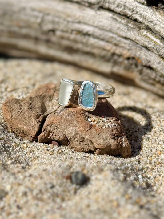Abalone and beach glass ring on a rock in sandy beach setting