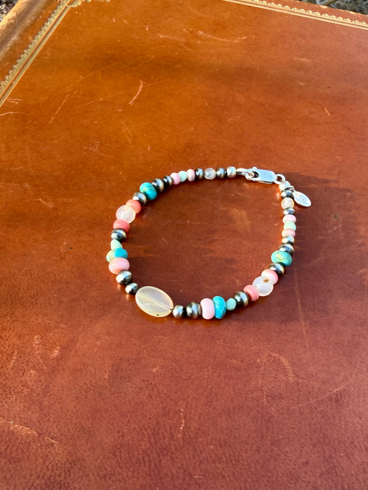 Close up of faceted Montana Agate Kingman turquoise and Pink Conch sterling silver bracelet