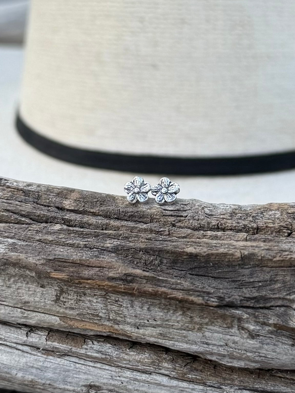 Close-up of sterling silver flower studs showing petal detail and smooth finish