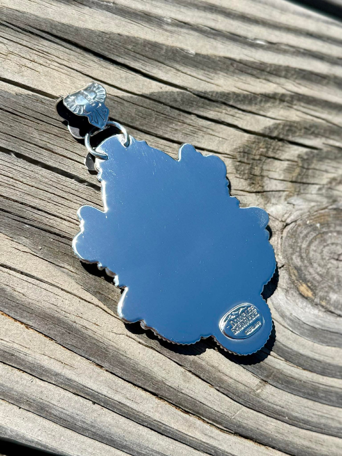 Back of sterling silver pendant showing handcrafted detail and bale