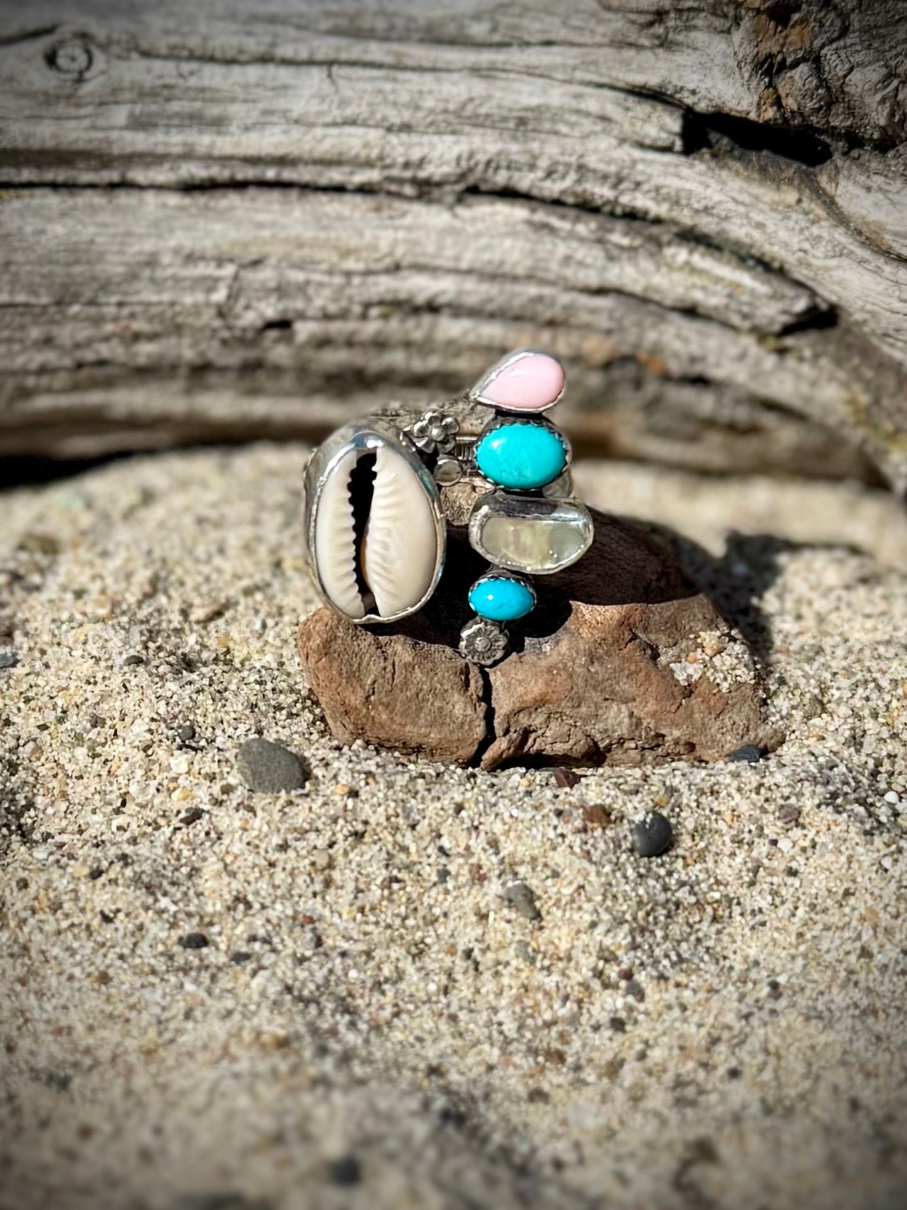 Multicolored stone ring on a rock with sand and wood in the background