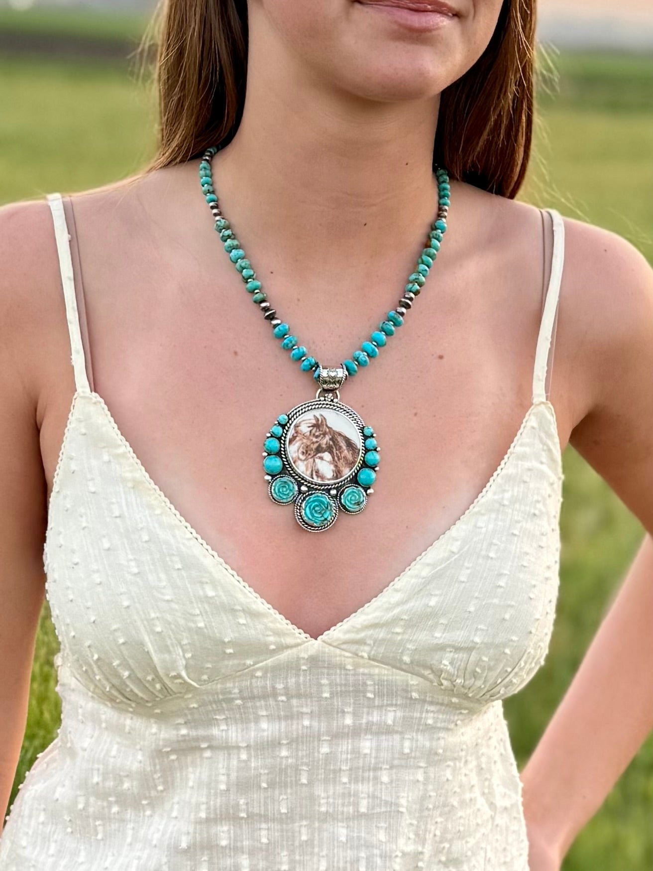 Woman wearing a horse  and turquoise pendant in a natural setting
