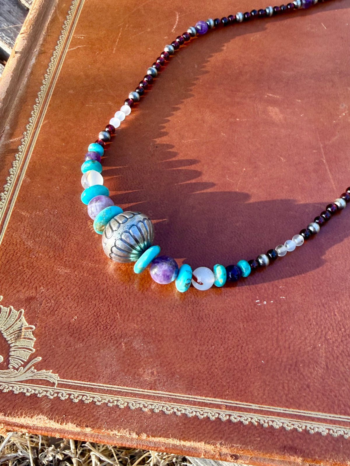 Close up of Montana Agate Amethyst Kingman turquoise Garnet and decorative sterling silver beads