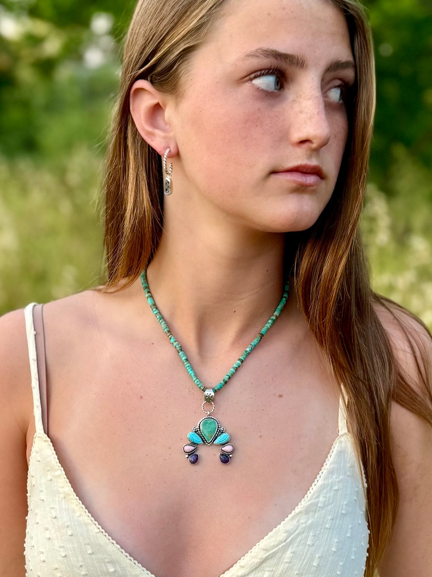 Woman wearing a turquoise pink conch and charoite pendant on a turquoise necklace
