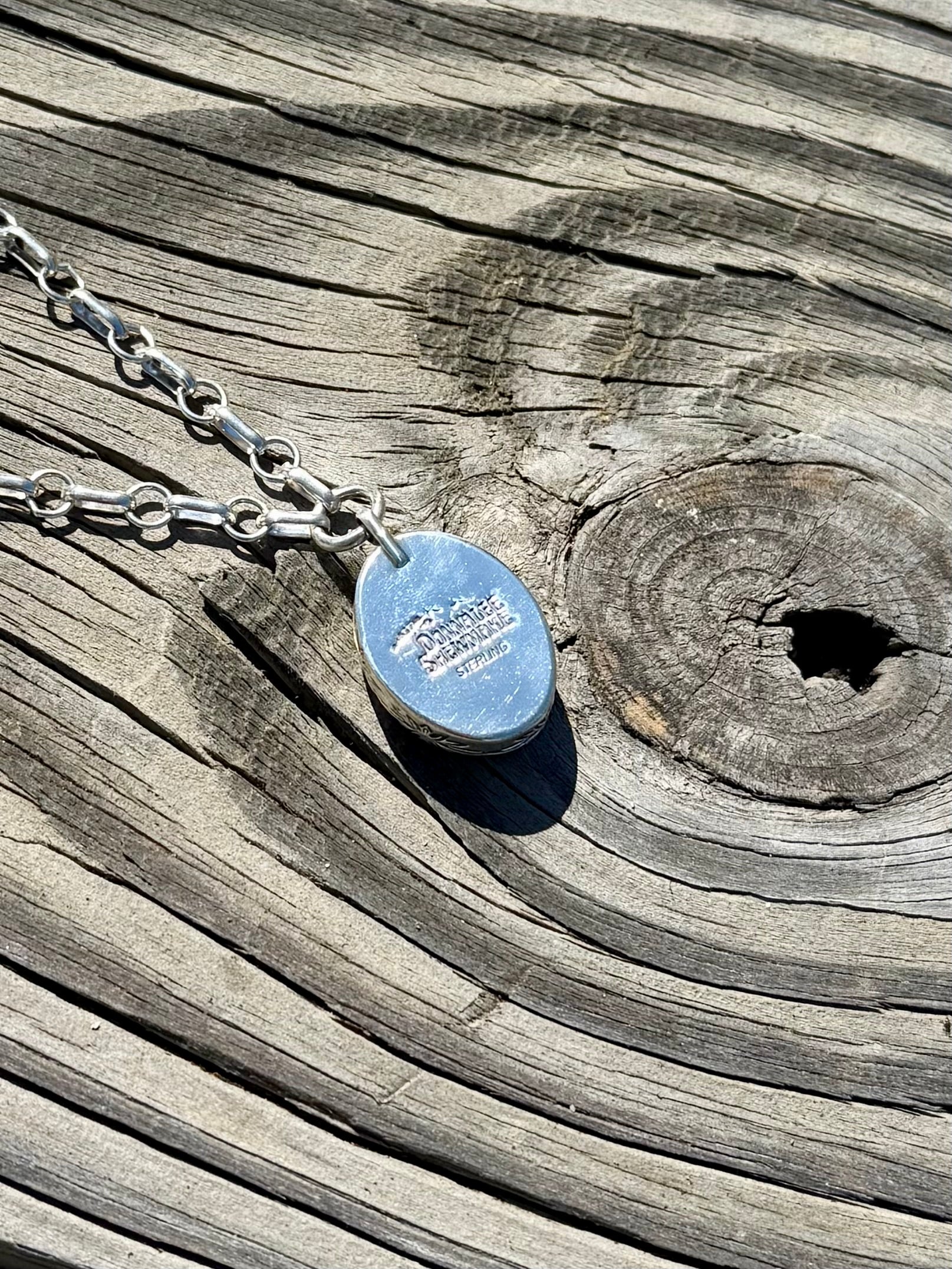 Back view of handcrafted sterling silver pendant with stamped details and chunky Royston turquoise bead necklace