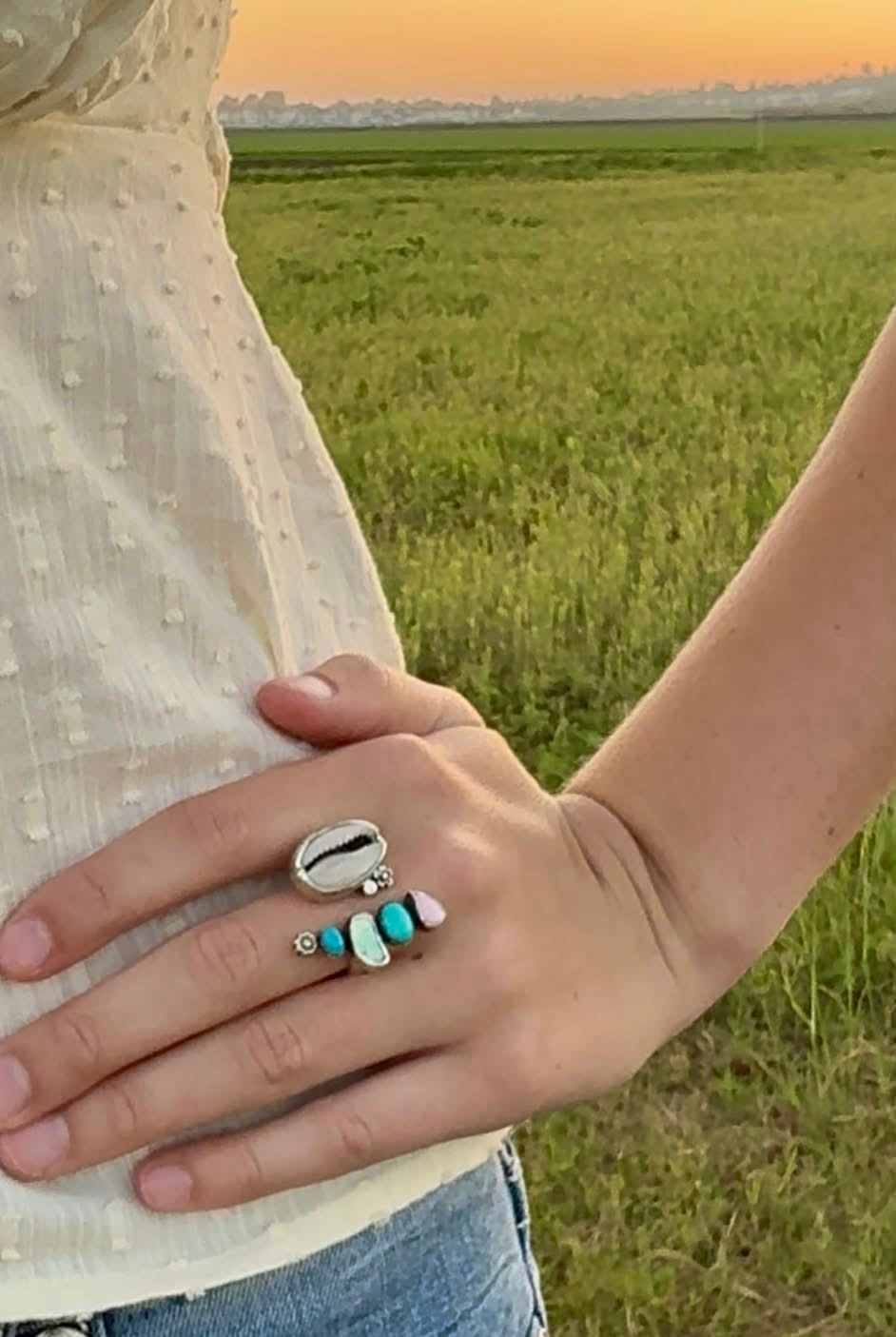 Person wearing a cowrie shell ring with turquoise and abalone shell coastal and boho in one ring