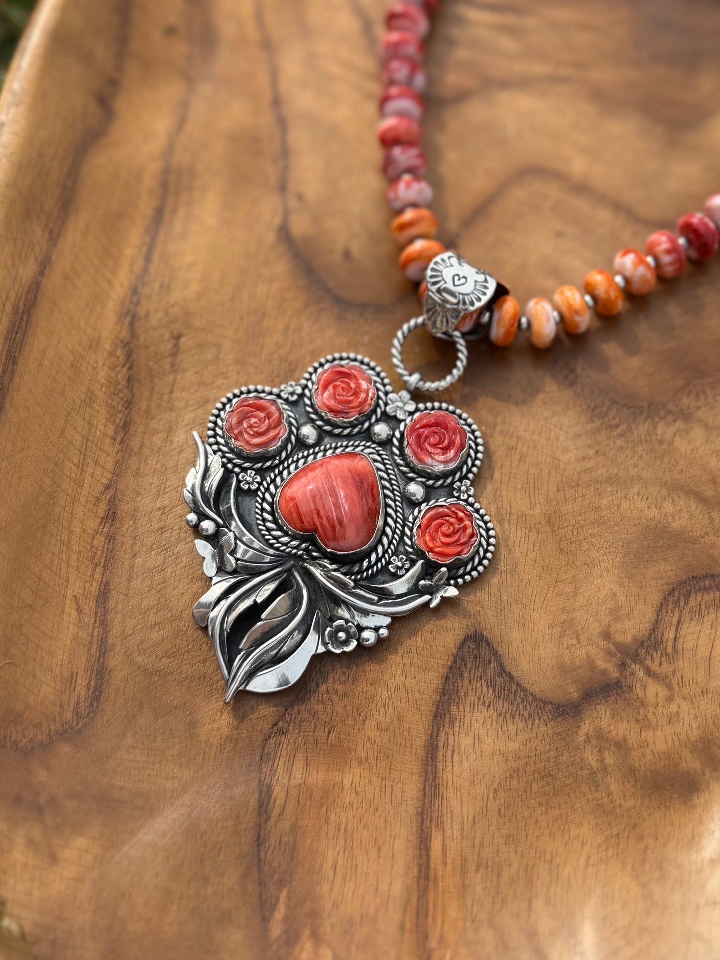 Close-up of red spiny oyster stones set in sterling silver paw pendant, detailed handcrafted dog lover jewelry
