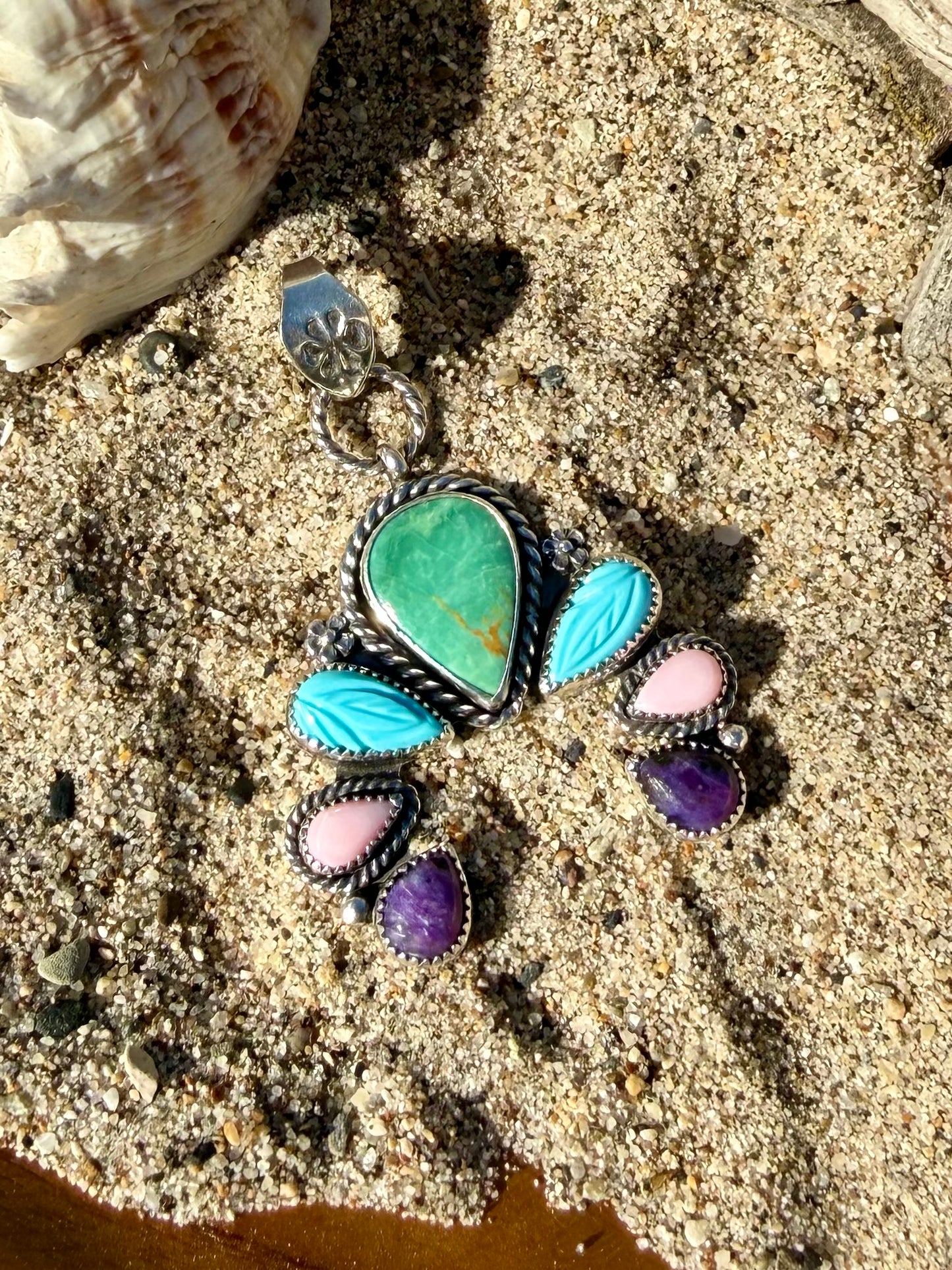 Close-up of hand carved turquoise stone set in sterling silver naja pendant showing detail