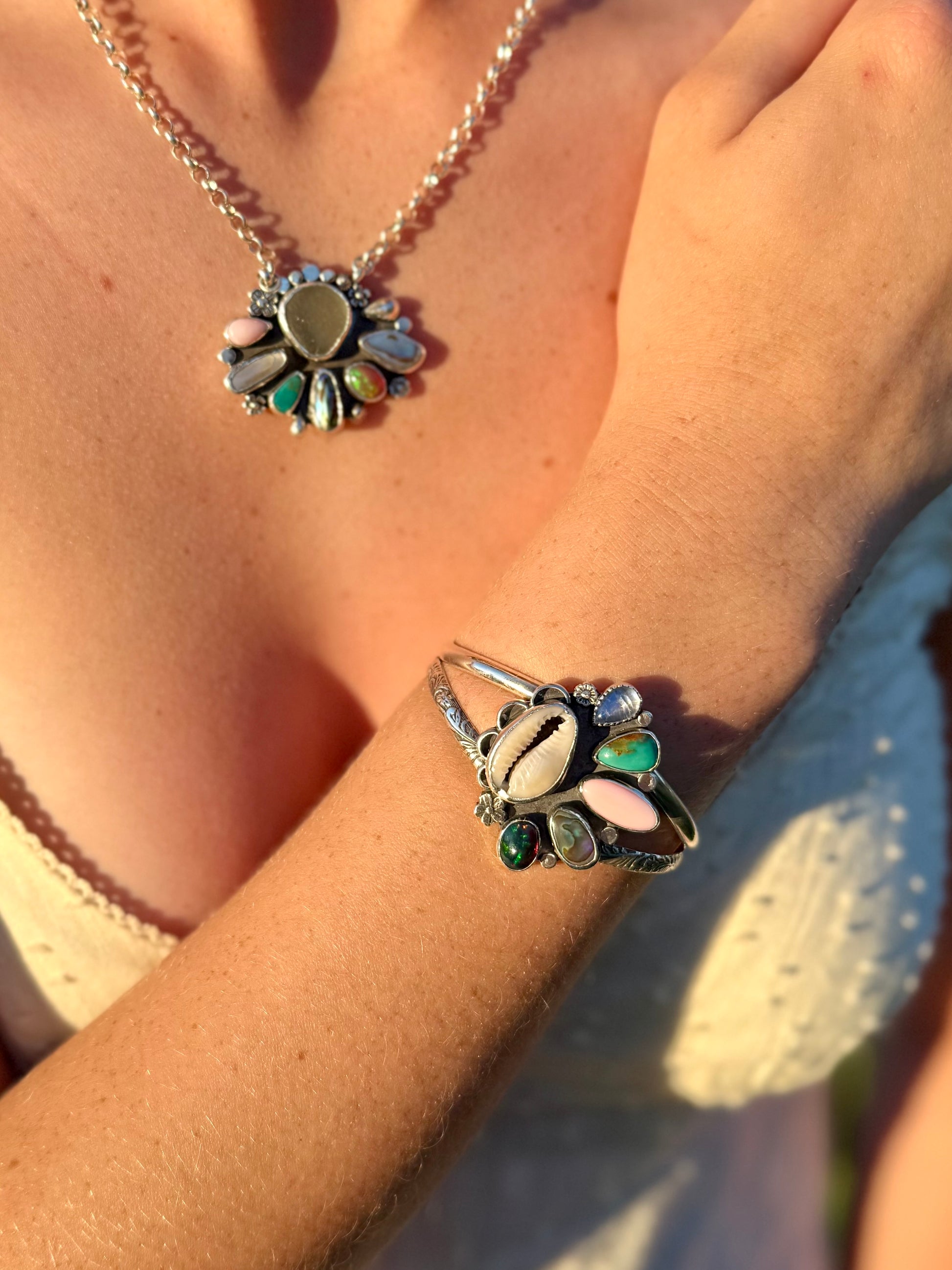 Close-up of a person wearing a multi stone silver bracelet with a floral design on their wrist.