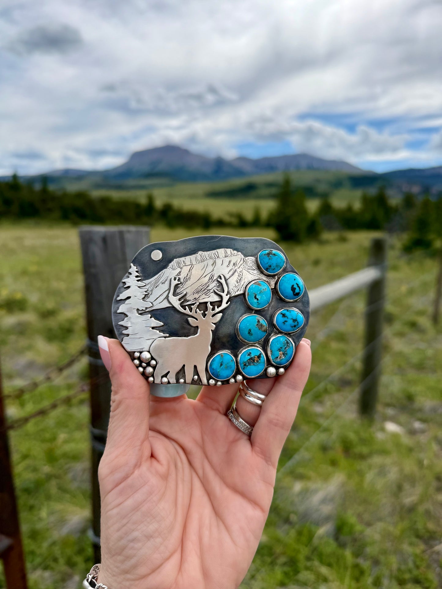 Close-up of Ithaca Peak Turquoise stones and hand engraved sterling silver elk Montana belt buckle.