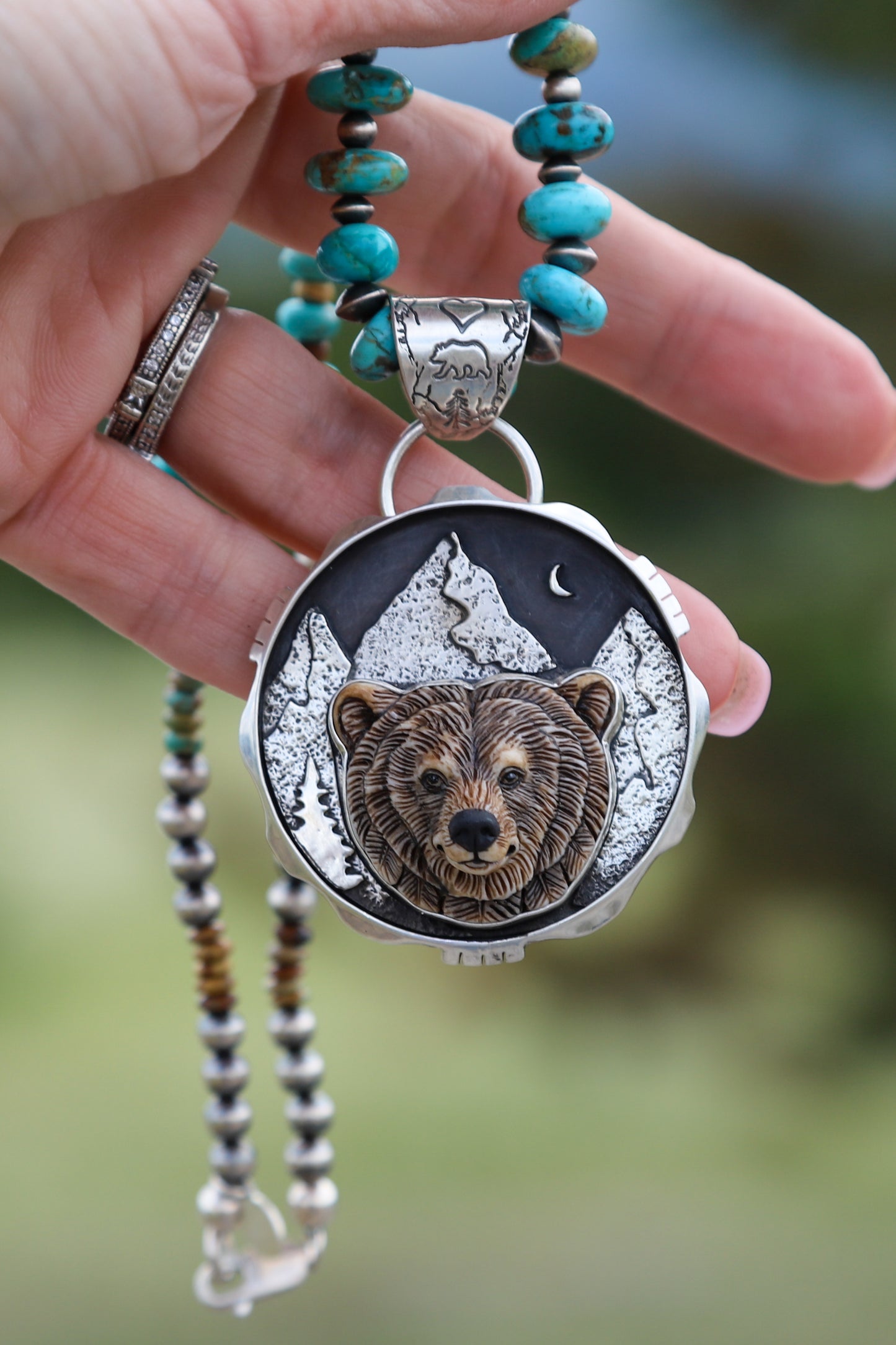 Handmade sterling silver Grizzly Bear pendant featuring a signed porcelain cabochon by Laura Mears with a mountain landscape and crescent moon, finished in a high polish.