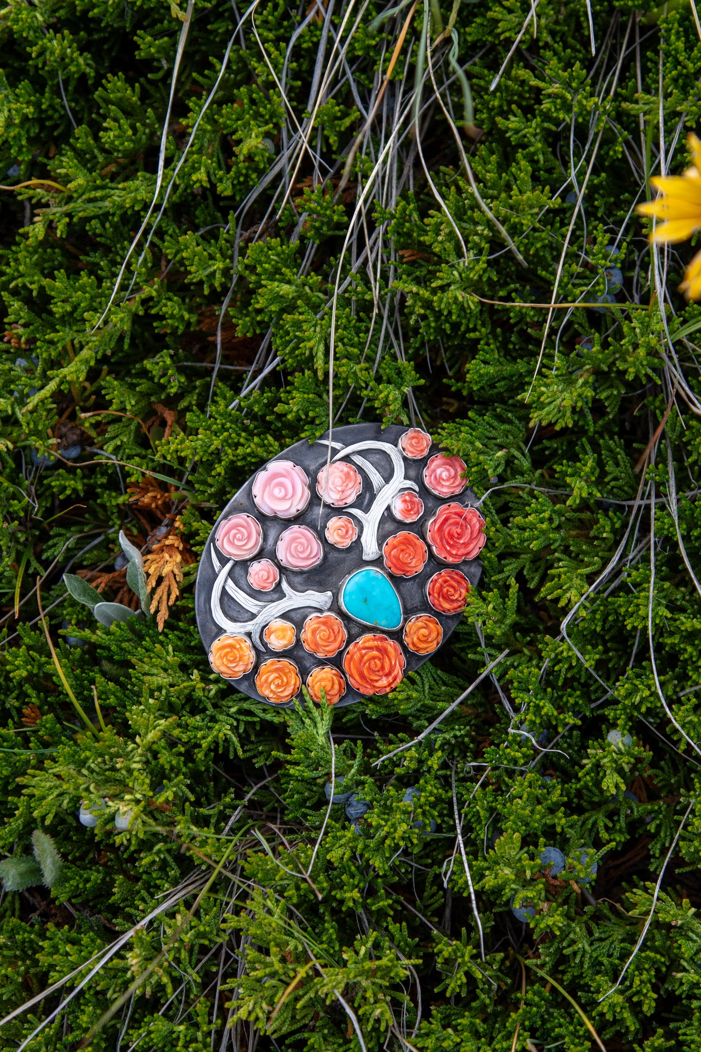 Handmade western belt buckle featuring ombré pink conch, red and orange spiny oyster roses surrounding a Royston Turquoise centerpiece with a hand-engraved sterling silver longhorn on a steel buckle base with fine silver bezels.
