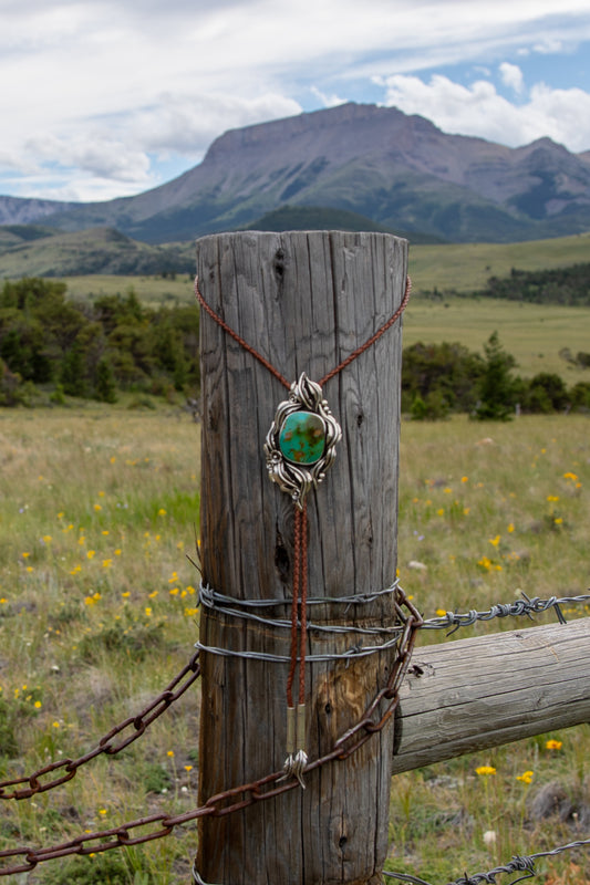 Handmade sterling silver Royston Turquoise bolo tie with flowing leaf and floral details, genuine braided leather cord, and hand-stamped Ear Mountain sterling silver tips from the Montana Collection.