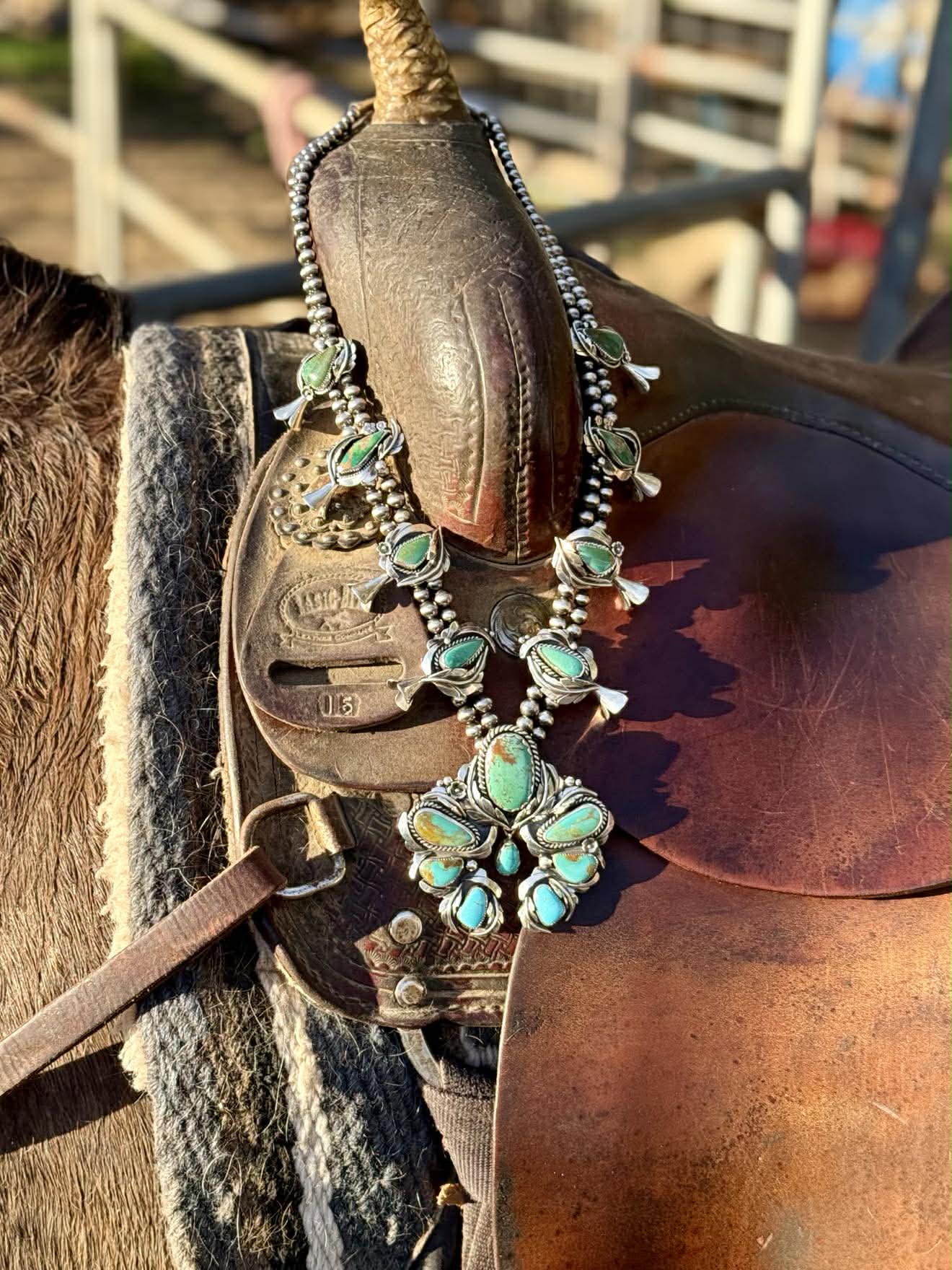 close detail of squash blossom necklace showing silver blossoms and turquoise stones
