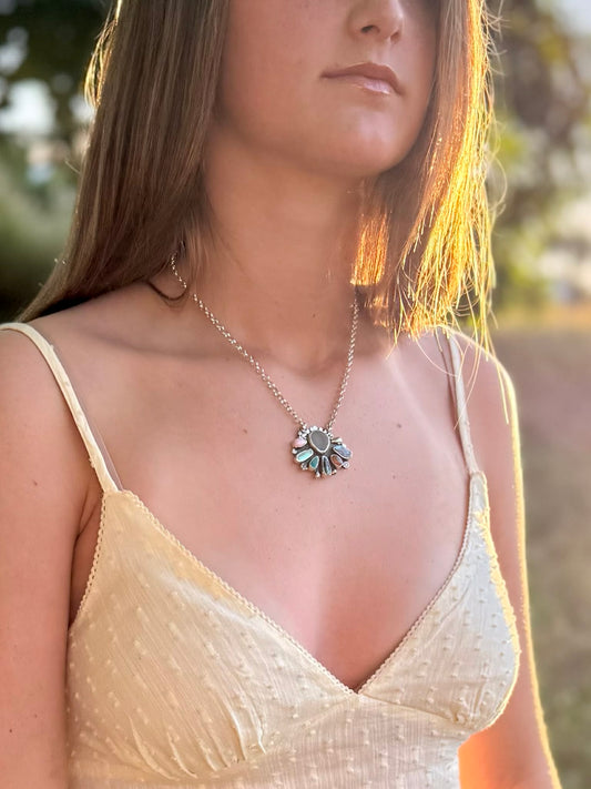 Woman wearing a delicate necklace with a floral pendant in a natural setting